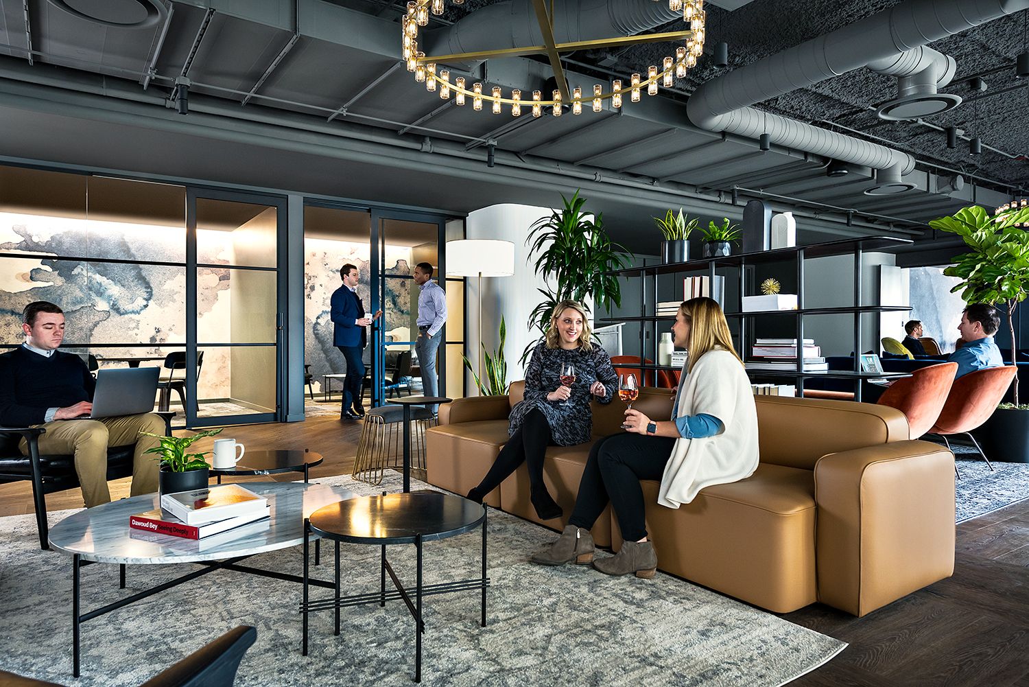 The image shows a spacious, modern office space with a large white arched ceiling, a large white sofa, a white coffee table, and a white rug on the floor.