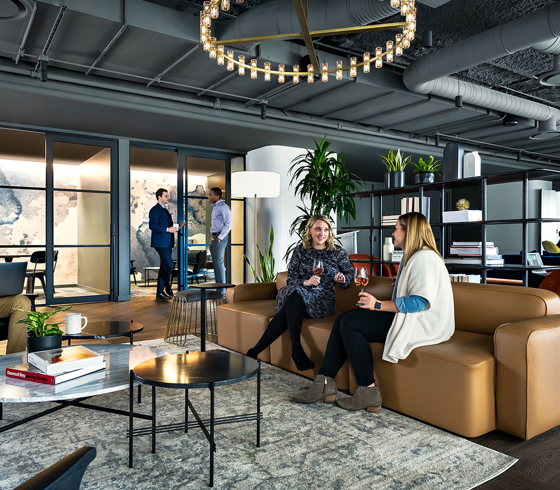 The image shows a spacious, modern office space with a large white arched ceiling, a large white sofa, a white coffee table, and a white rug on the floor.