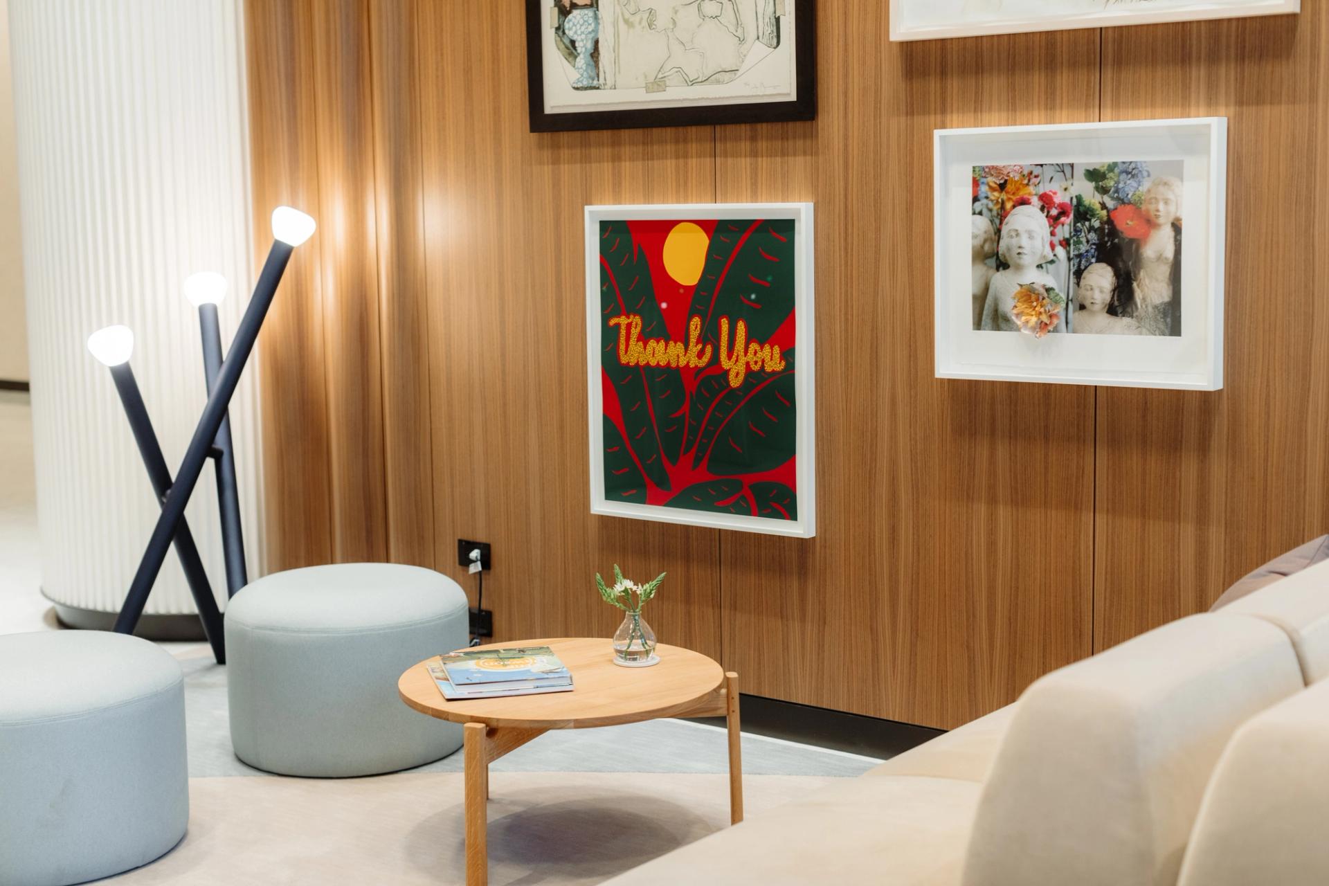 Cozy lounge area at 525 West Monroe with modern seating, round ottomans, a small wooden table, and framed artwork on wood-paneled walls, including a piece with the words 'Thank You'.