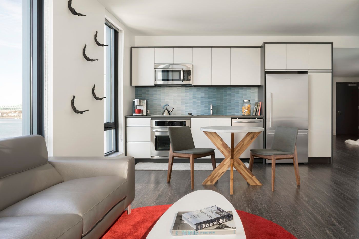 Model kitchen and living room at The Eddy Apartments for rent in East Boston, featuring wood grain floor paneling.