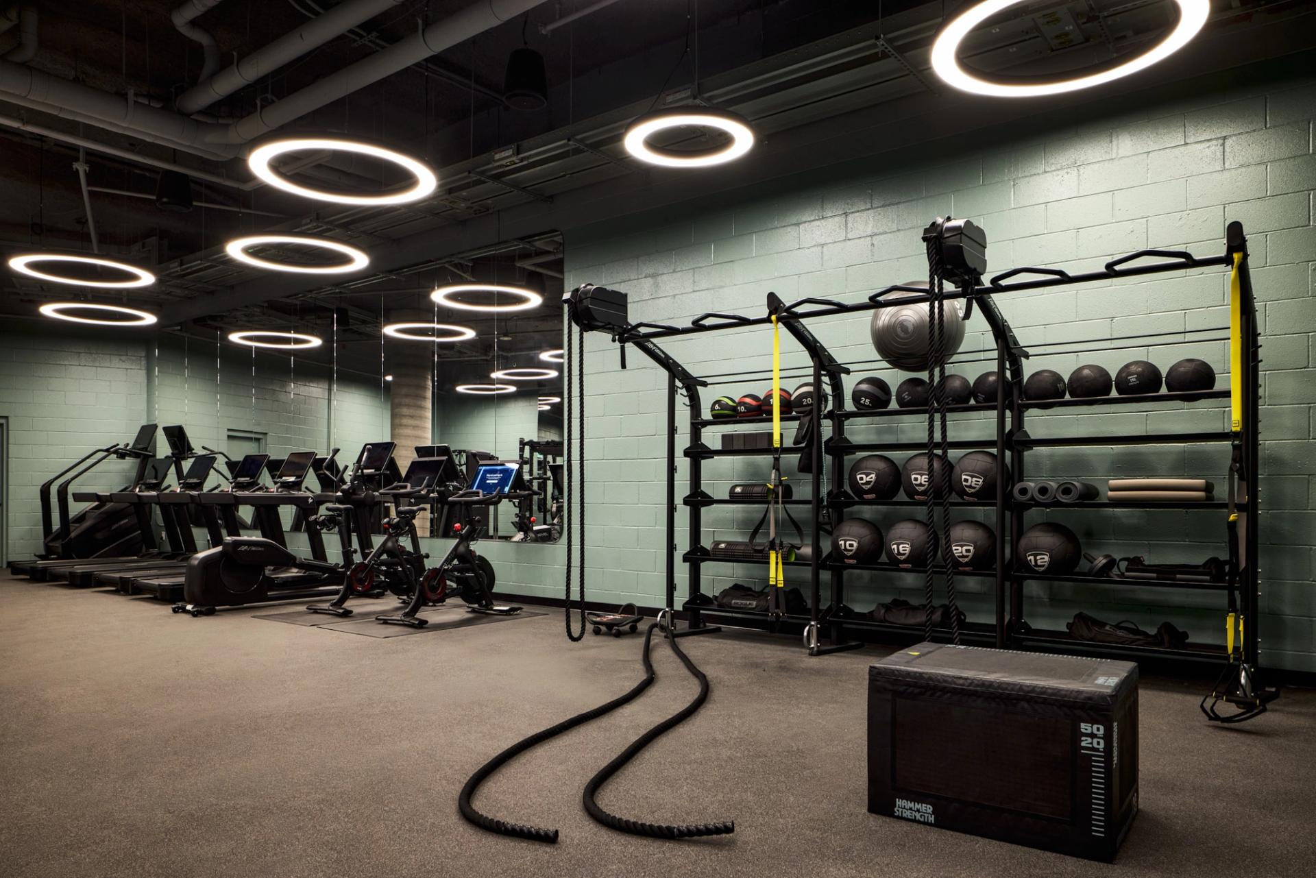 The fitness center at Verra Apartments for rent in Boston, featuring cardio equipment and mirrored walls.