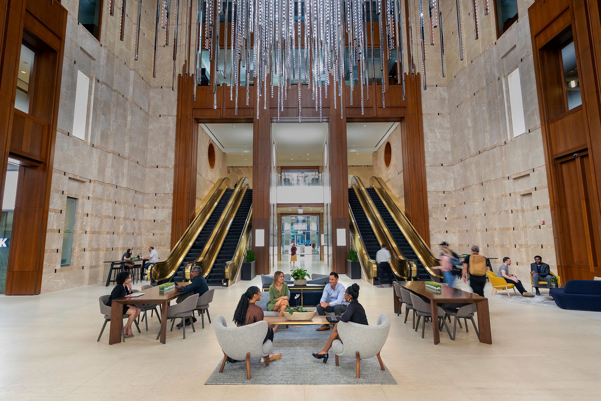 Spacious modern lobby with escalators, seating areas, and people talking and walking