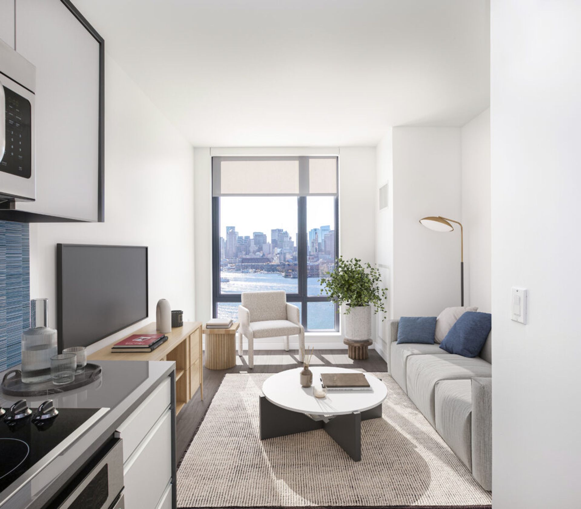 Model living room and kitchen at The Eddy Apartments for rent in East Boston, featuring wood grain floor paneling.