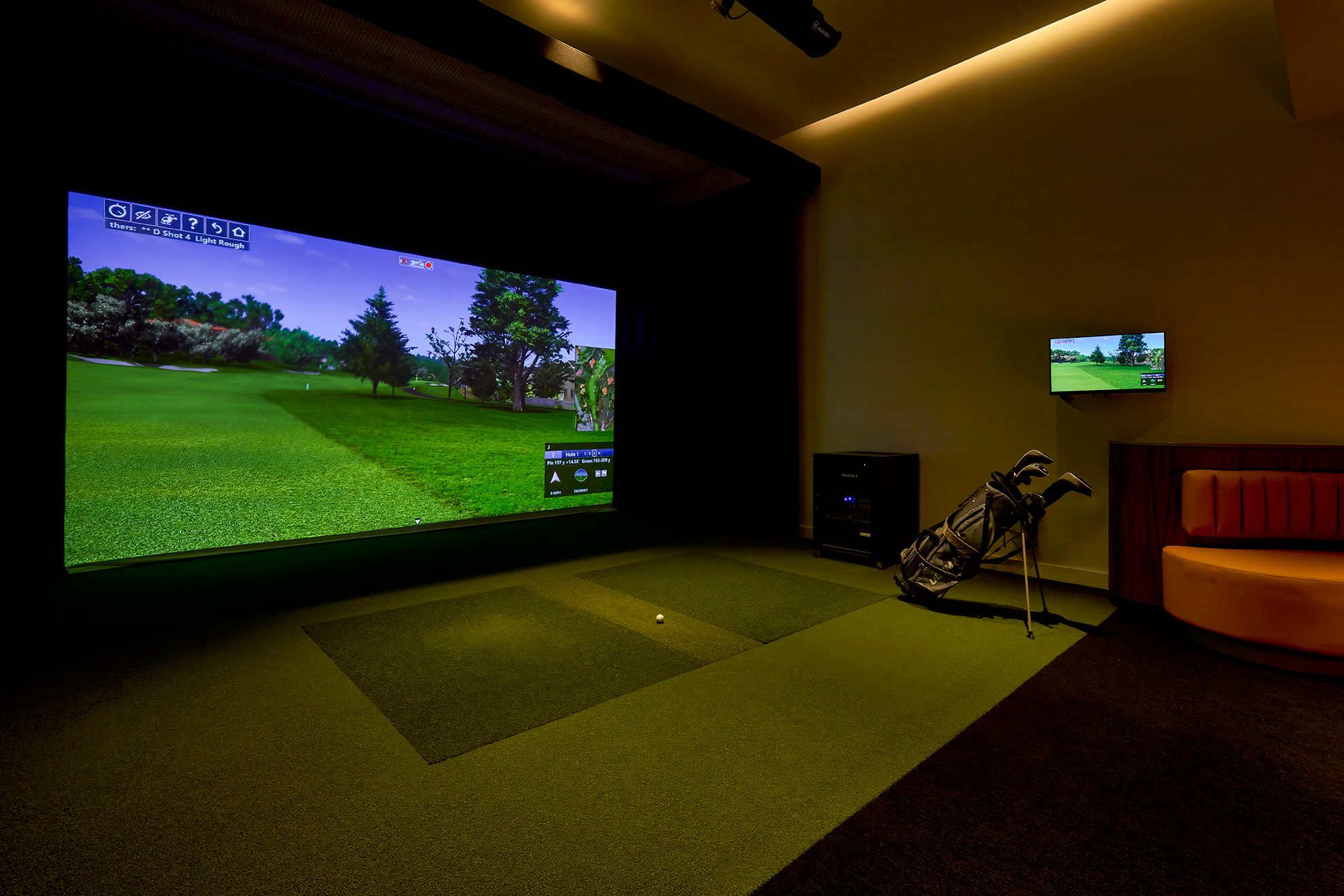 Man practices golf swing in the games simulator lounge in the Residences at Mazza