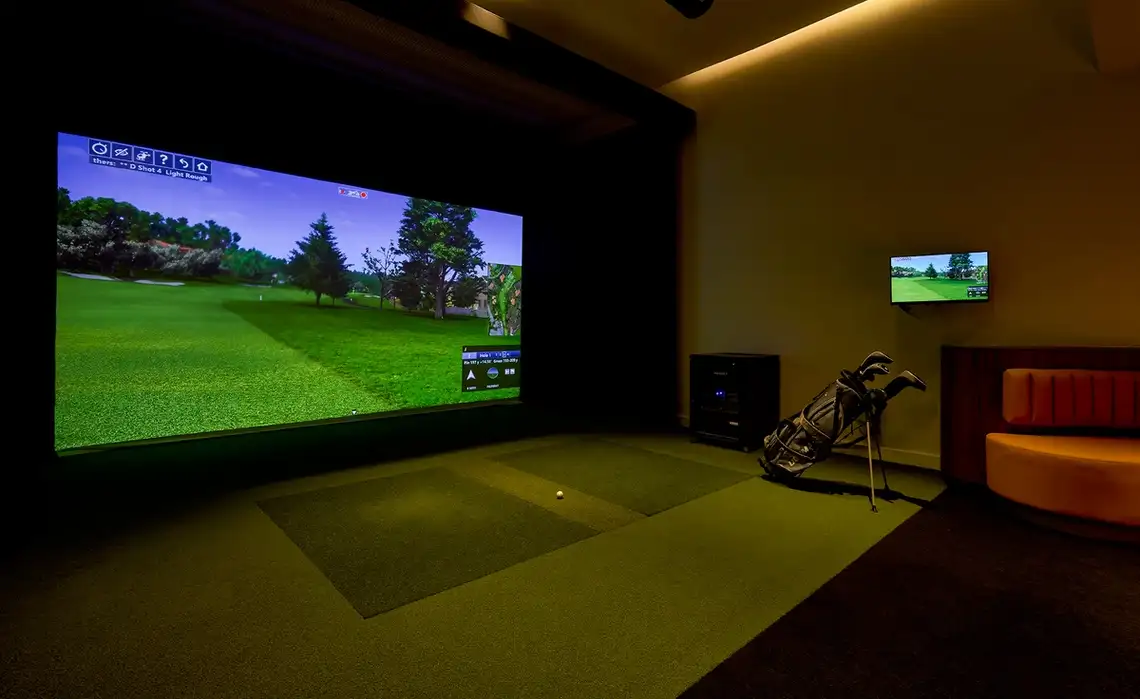 Man practices golf swing in the games simulator lounge in the Residences at Mazza