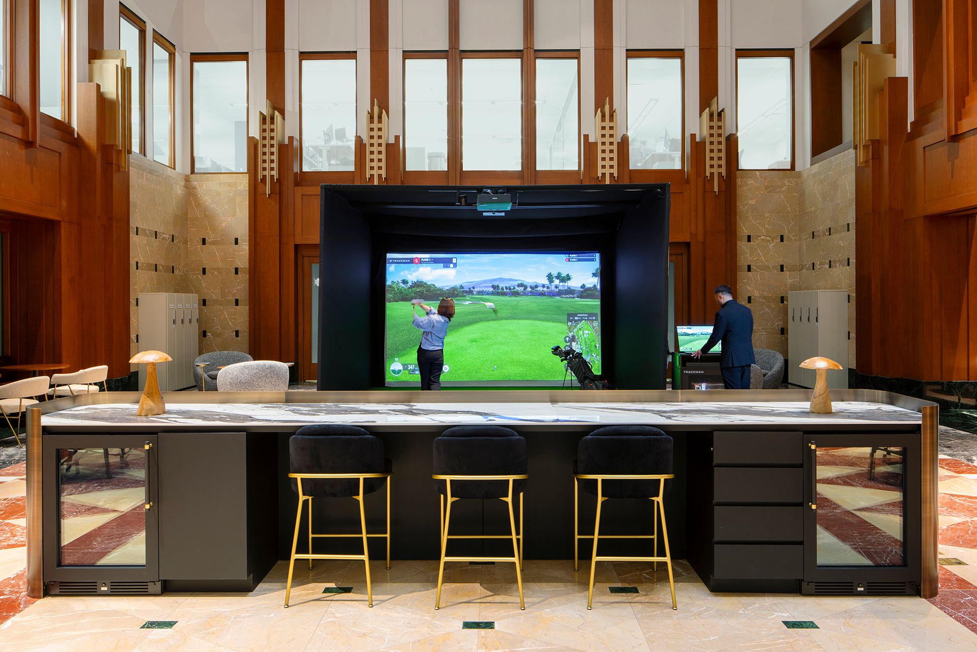 People playing indoor virtual golf in a spacious room with wood paneling and modern seating