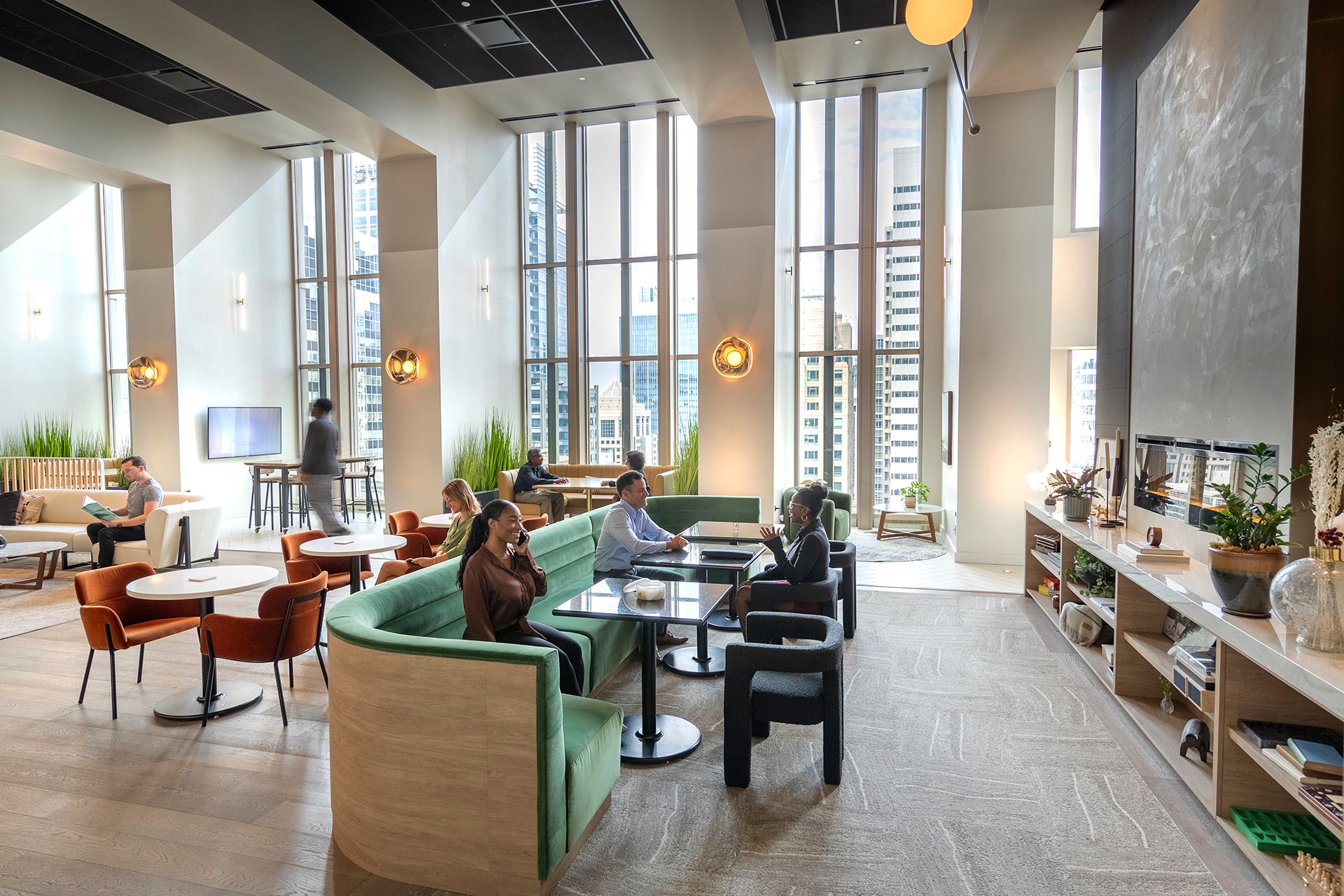 People sitting and talking in a modern office lounge with large windows and city views