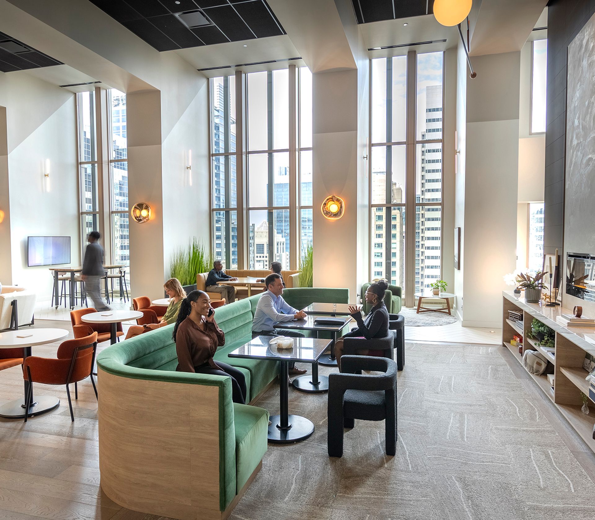 People sitting and talking in a modern office lounge with large windows and city views