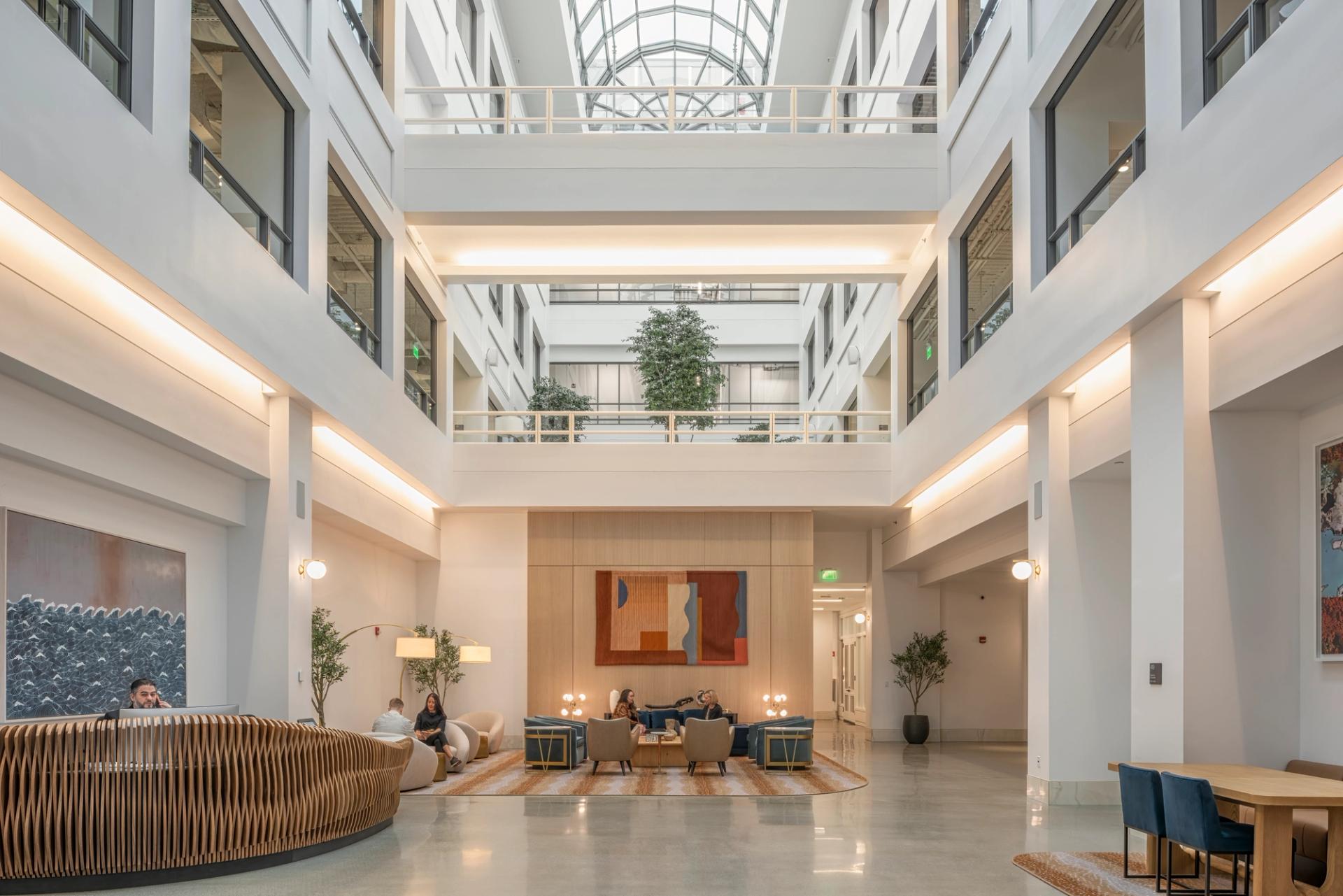 Bright and spacious modern office lobby with seating areas and large windows letting in natural light.