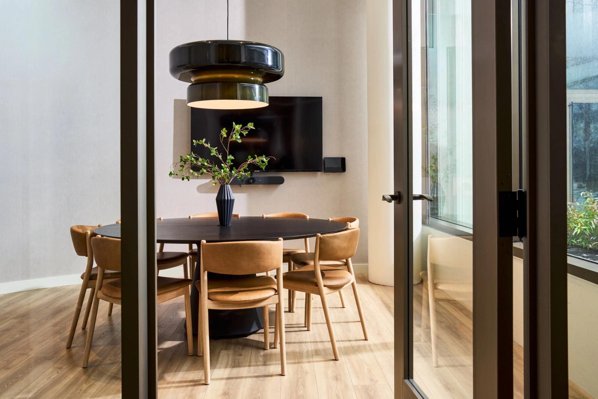 Meeting room at Verra Apartments for rent in Boston, featuring a conference table with chairs and a computer.