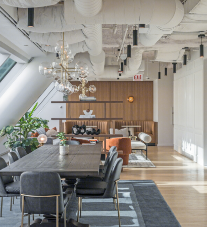 23rd floor clubhouse at 525 West Monroe featuring a long dark wood dining table with black chairs, modern glass globe chandeliers, booth seating with wood panel walls, and open shelving accents.
