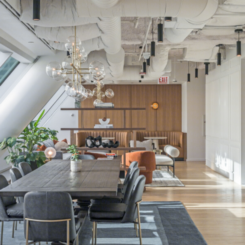 23rd floor clubhouse at 525 West Monroe featuring a long dark wood dining table with black chairs, modern glass globe chandeliers, booth seating with wood panel walls, and open shelving accents.