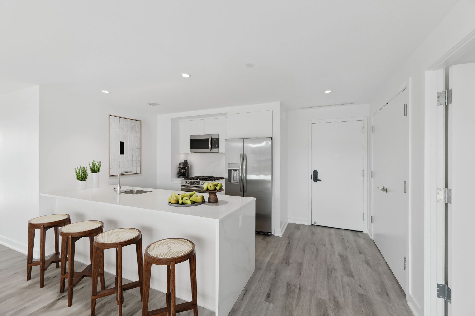 Model kitchen at Crossing DC apartments in Navy Yard, featuring stainless steel appliances and white countertops.
