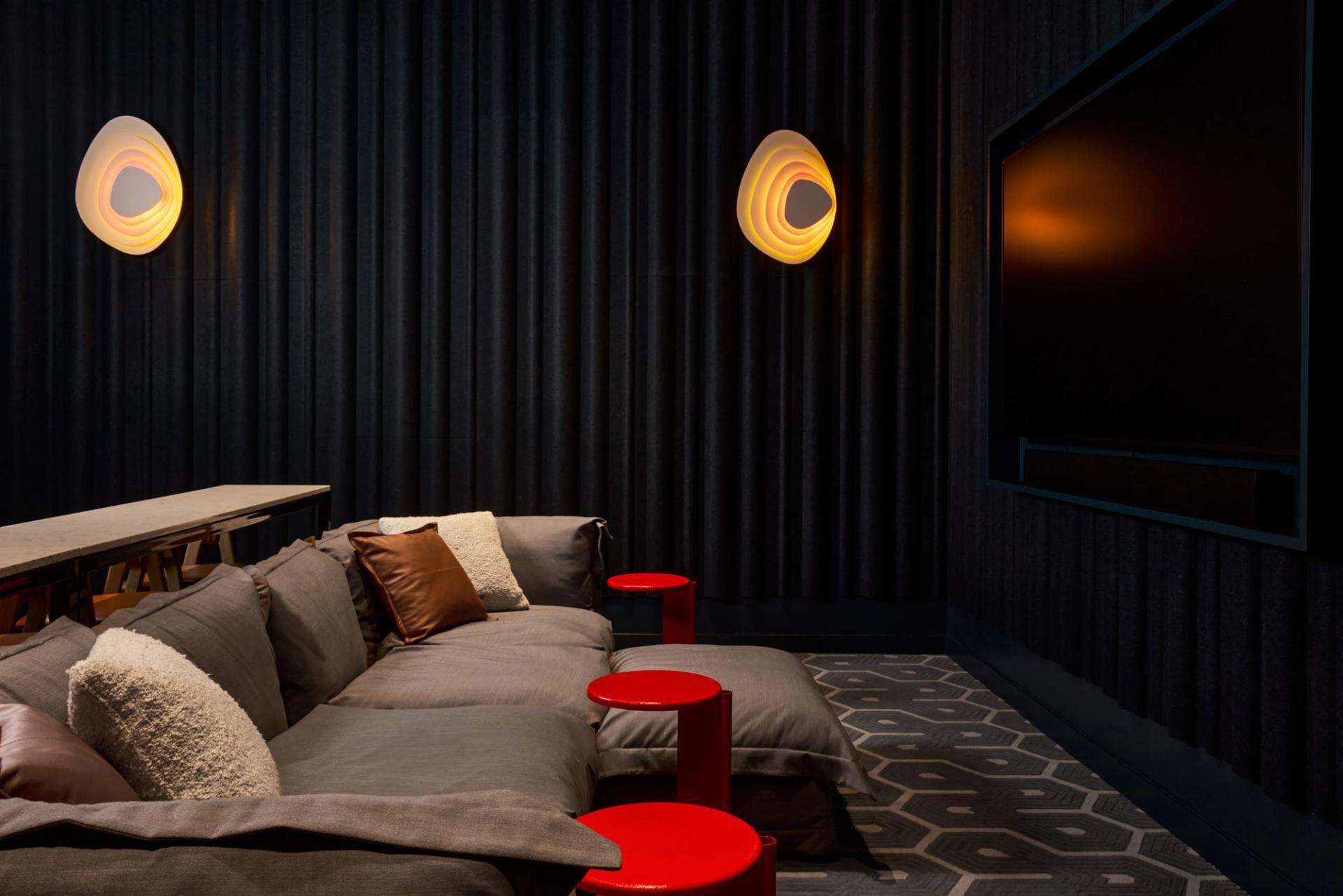 The theater room and lounge at Verra Apartments for rent in Boston, featuring cushioned chairs and a flat screen TV.