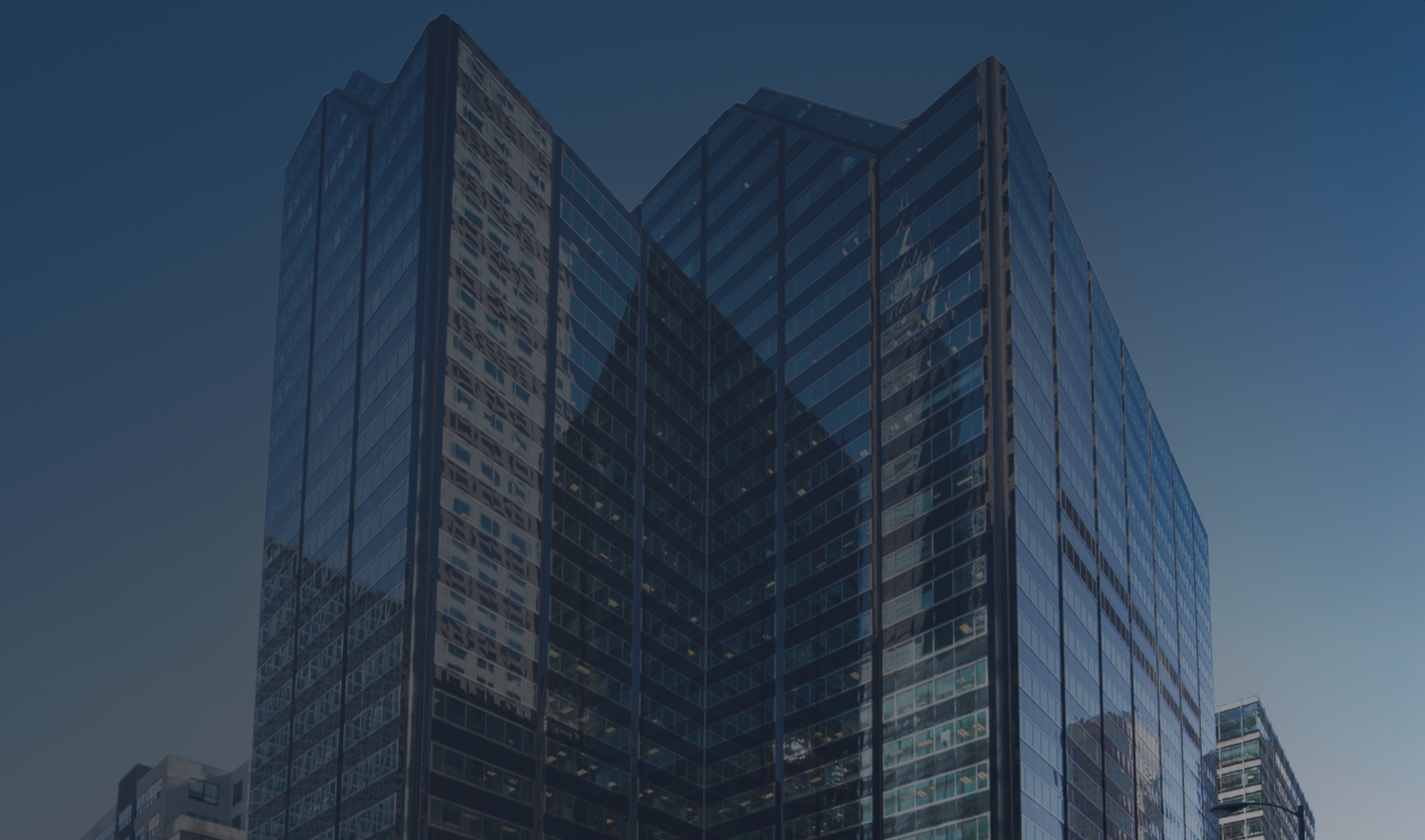Exterior view of 525 West Monroe, a modern glass skyscraper in Chicago with a distinctive facade, reflecting the blue sky and nearby buildings.