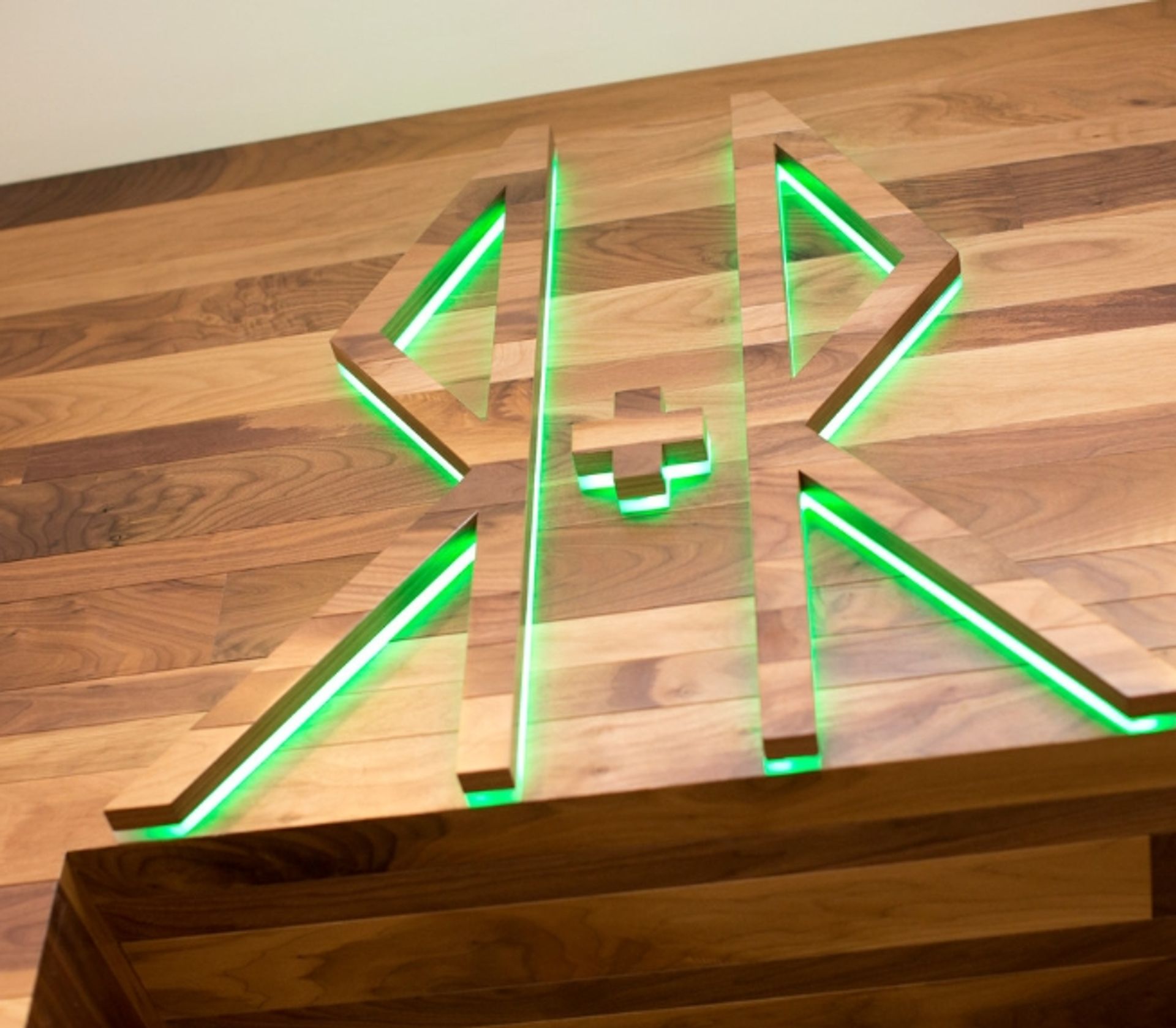Wooden letters RR with a plus sign in the middle, backlit with green light on a wooden surface
