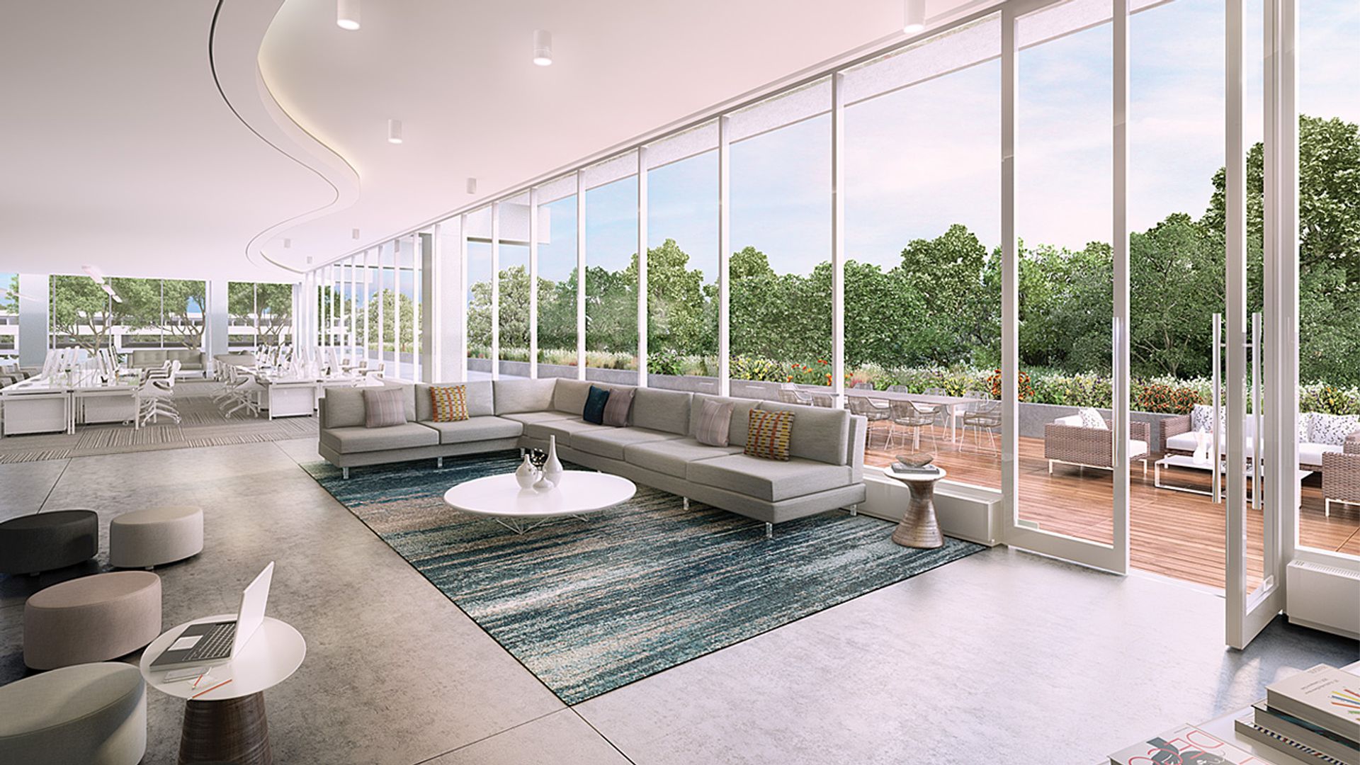 A modern living room with a large, white sofa, a blue rug, and a glass wall view of trees, featuring a white coffee table, a blue vase, and a white chair.