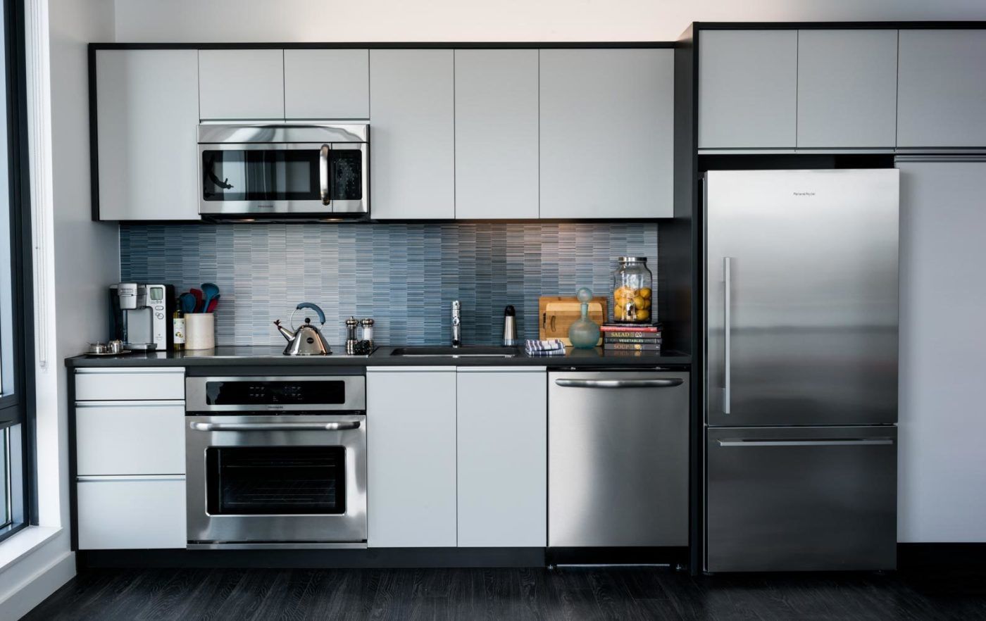 Model kitchen at The Eddy Apartments for rent in East Boston, featuring stainless steel appliances and tiled backsplash.