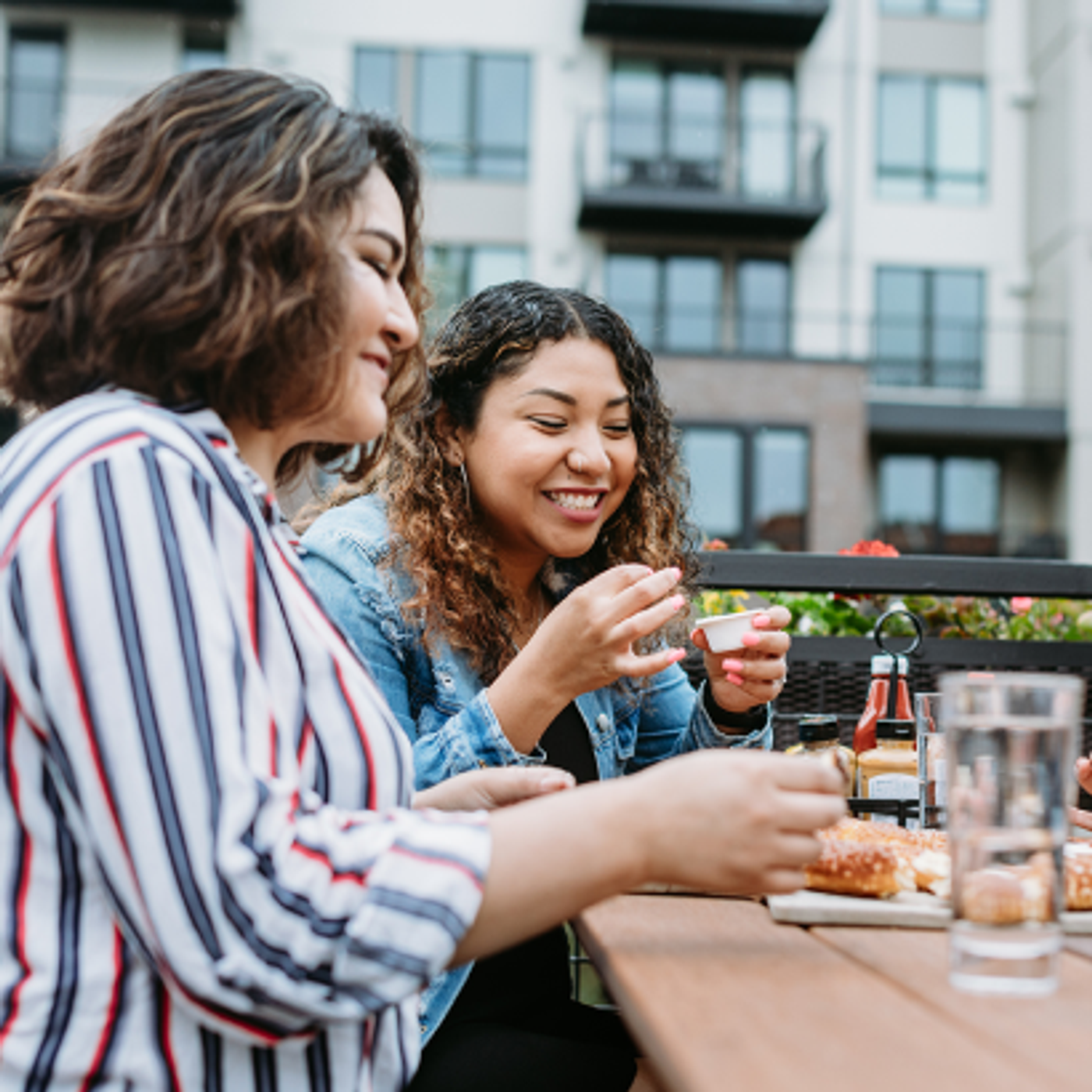 People sitting at an outdoor patio table near 525 West Monroe, enjoying food and drinks with modern residential buildings in the background.