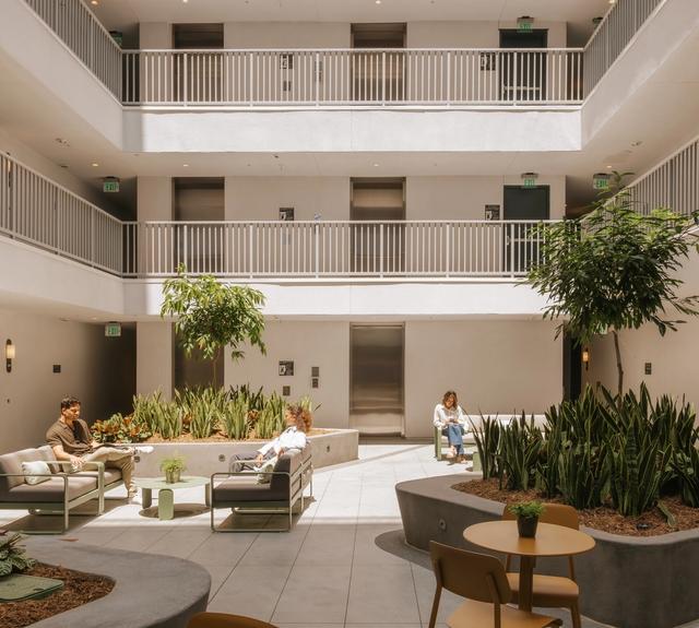 An open air courtyard with lush landscaping and inviting seating designed for gathering, unwinding, and enjoying the outdoors