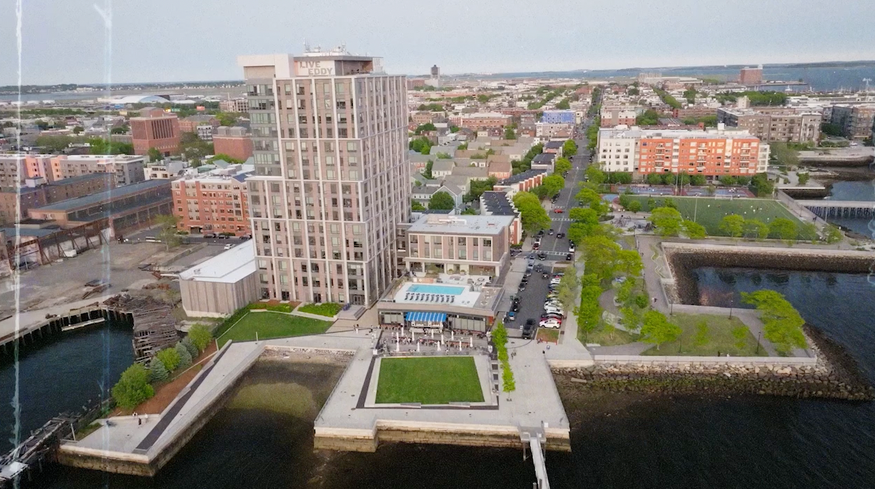 Aerial view of The Eddy Apartments for rent in East Boston, featuring a modern facade and outdoor pool.
