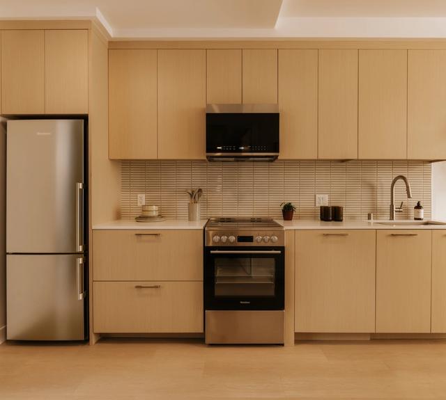 Kitchens with white oak cabinetry, mosaic tile backsplash, and stainless appliances