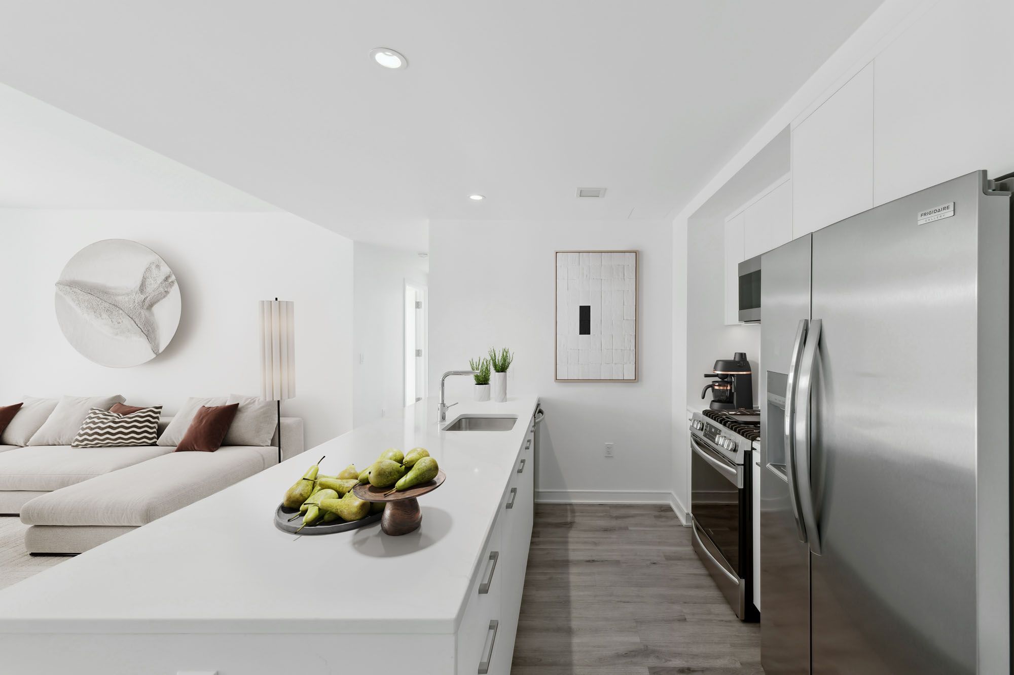 Model kitchen at Crossing DC apartments in Navy Yard, featuring stainless steel appliances and white countertops.