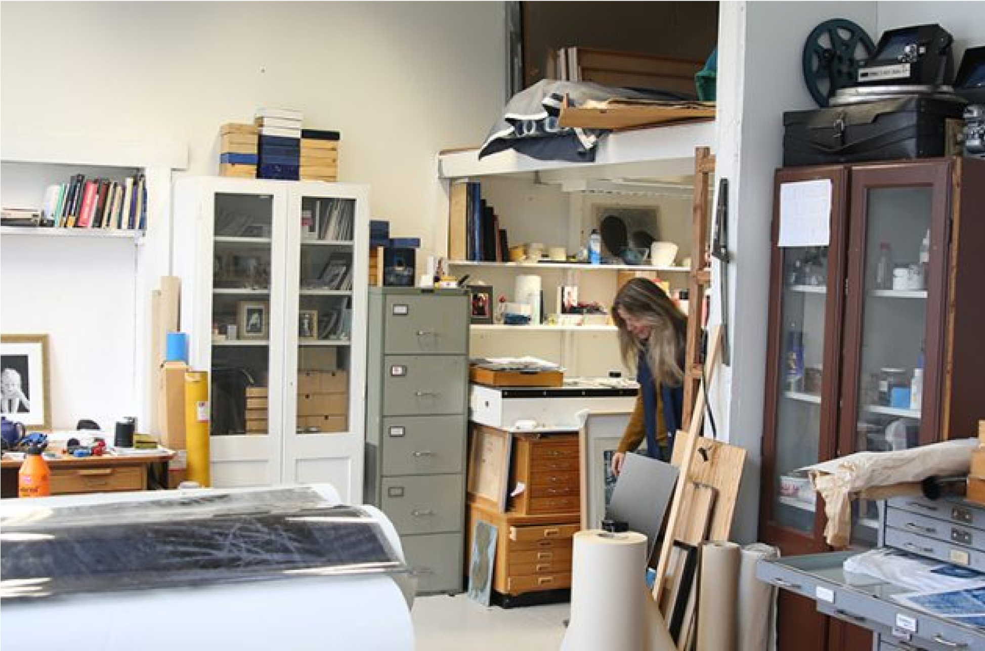 En person står inne på et arkivrom, hvor det er skuffer og skaper rundt om i rommet som bugner av materialer.