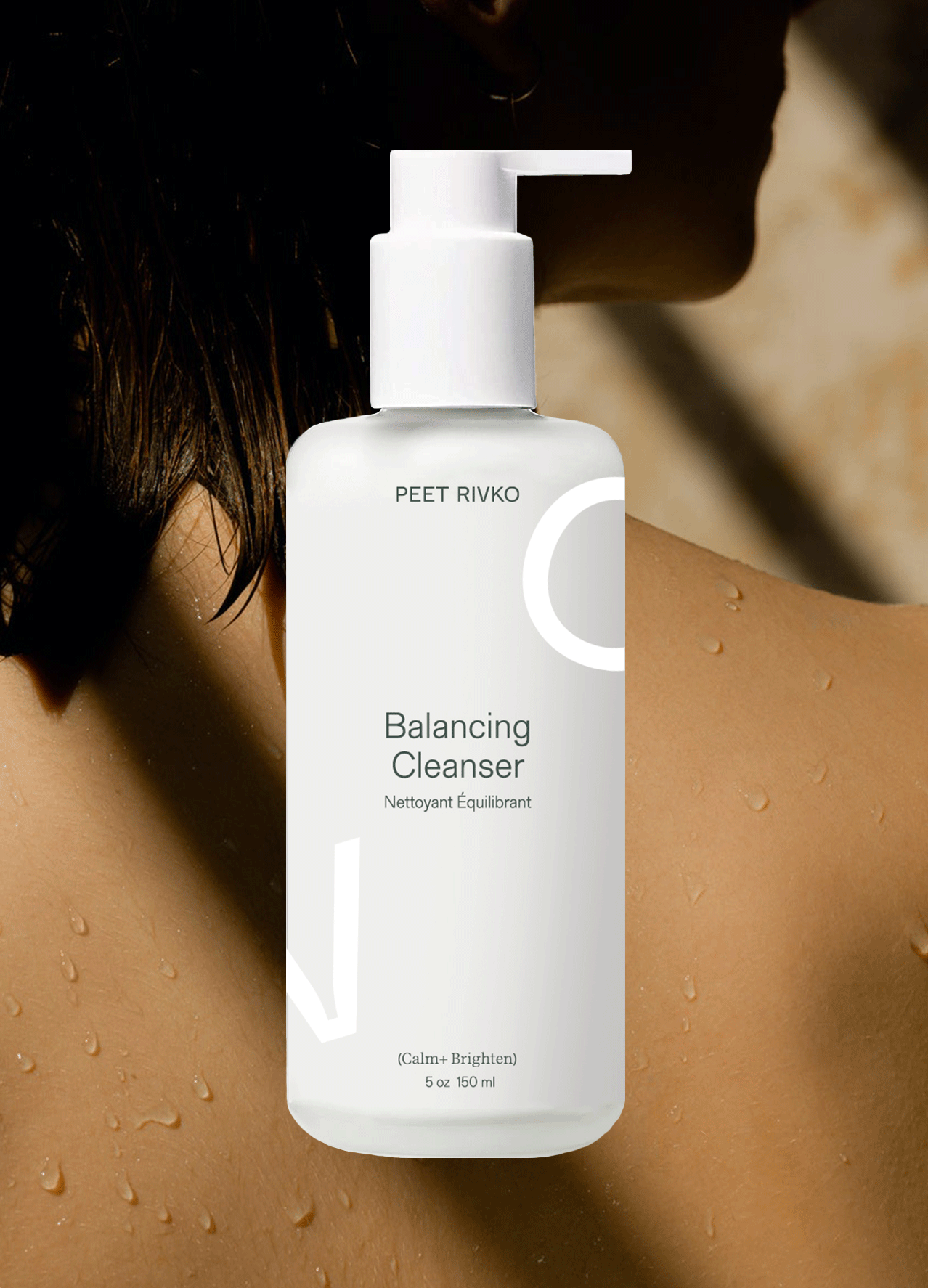 A white bottle of "Balancing Cleanser" displayed against a blurred background, featuring droplets on skin.