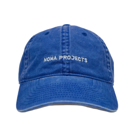 A blue cap featuring the text "NOMA PROJECTS" embroidered in white on the front.