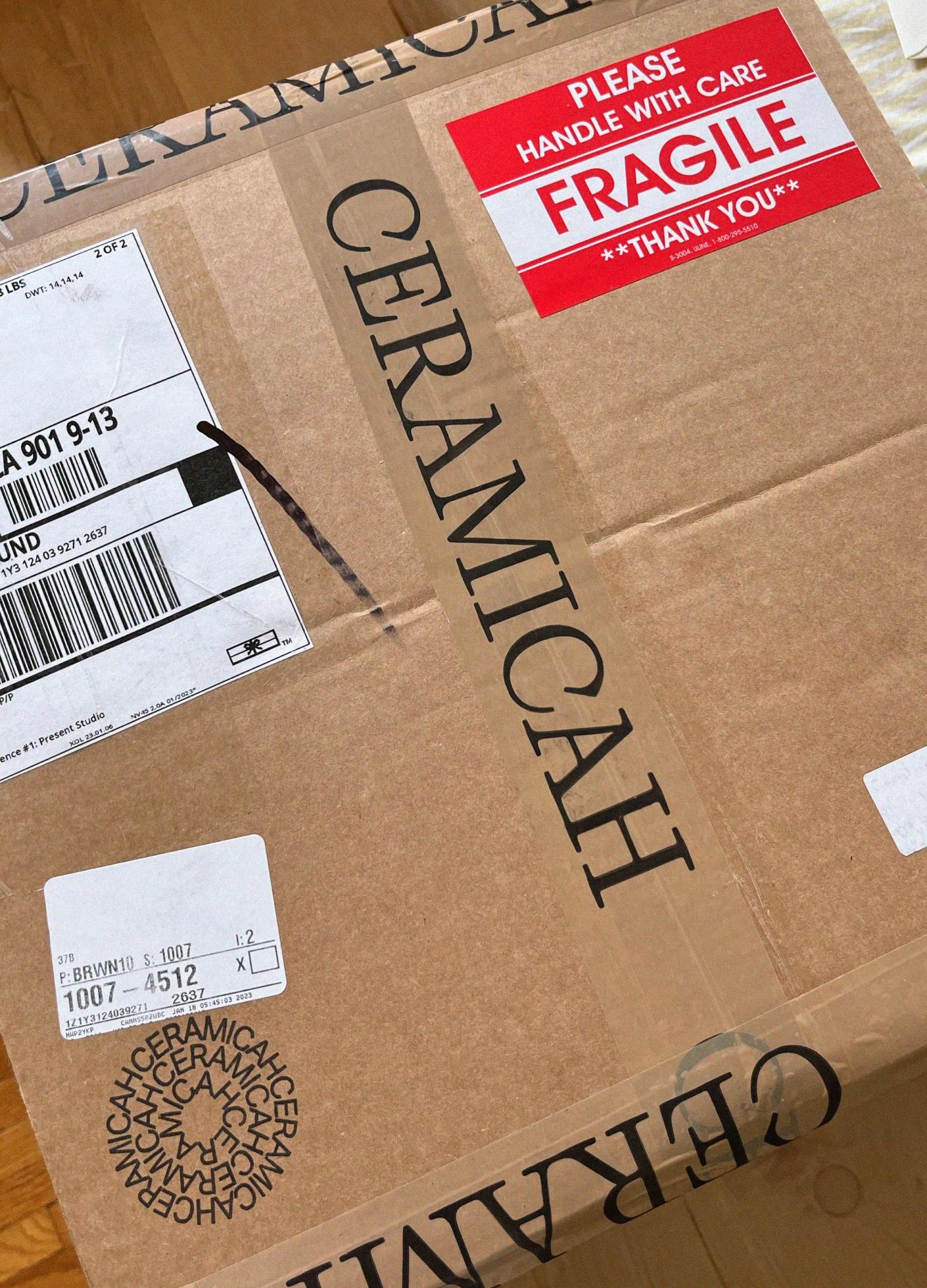 A cardboard box labeled "CERAMICAH" with a red "Fragile" sticker and shipping information visible on the side.