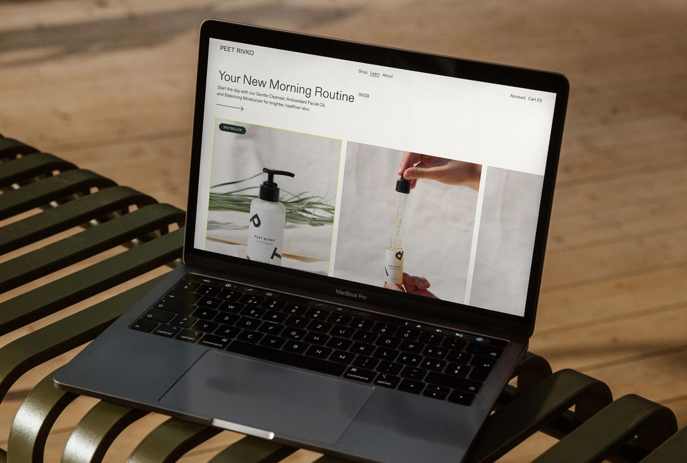 A laptop displays a skincare website featuring products like a cleanser and facial oil on a wooden table.