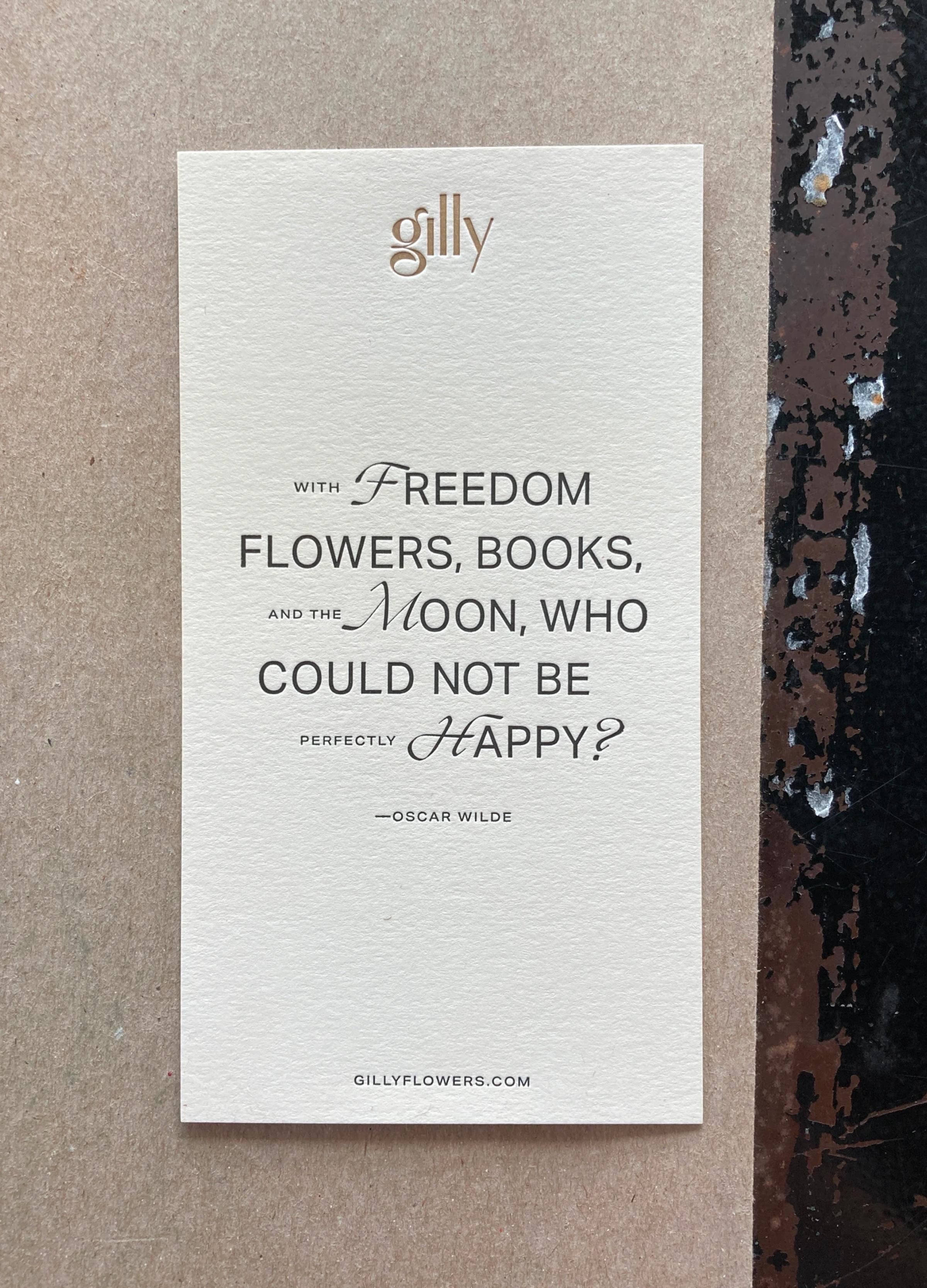 An elegant card with a quote by Oscar Wilde about happiness, printed on textured beige paper with a website link.