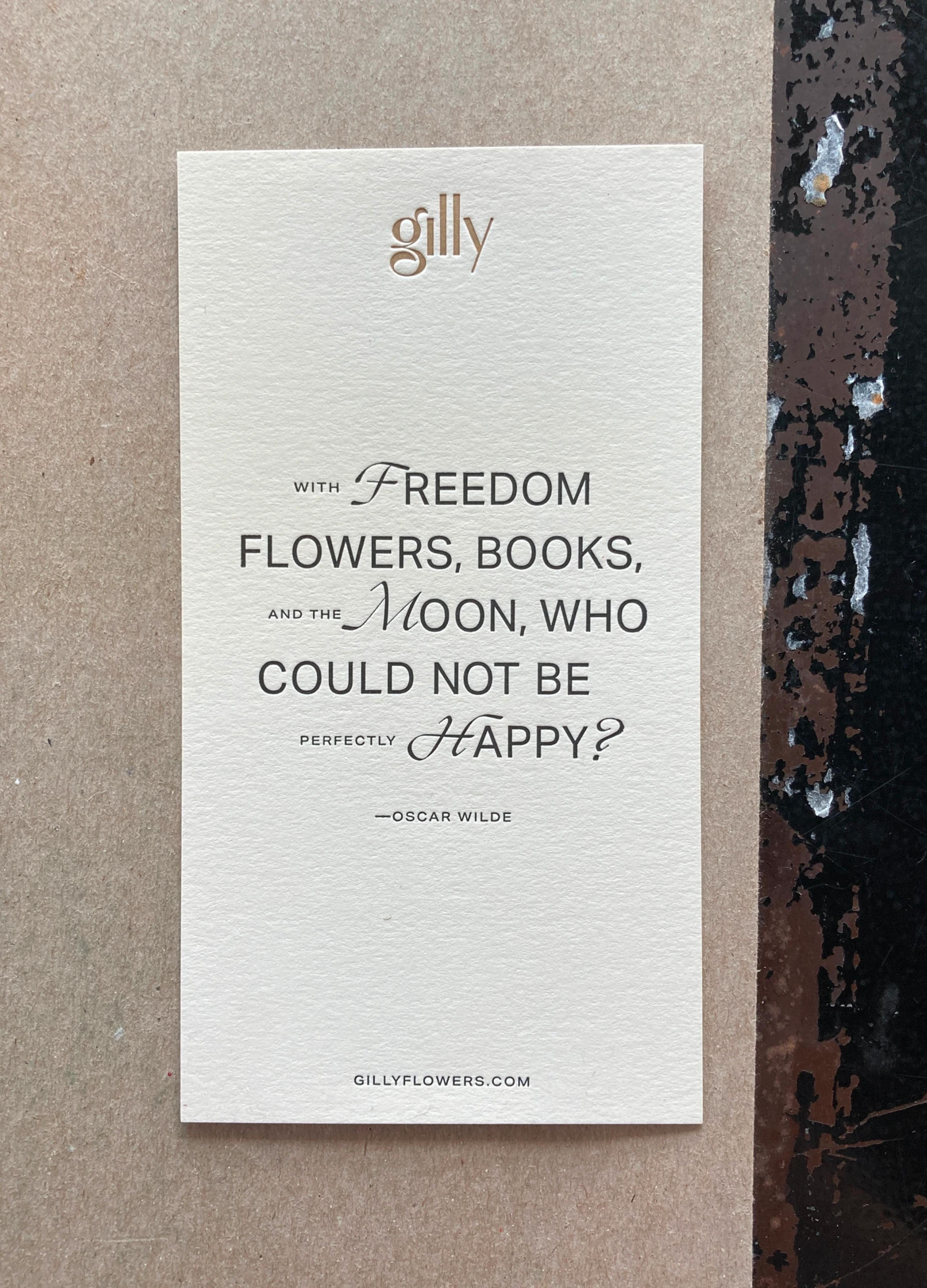 An elegant card with a quote by Oscar Wilde about happiness, printed on textured beige paper with a website link.