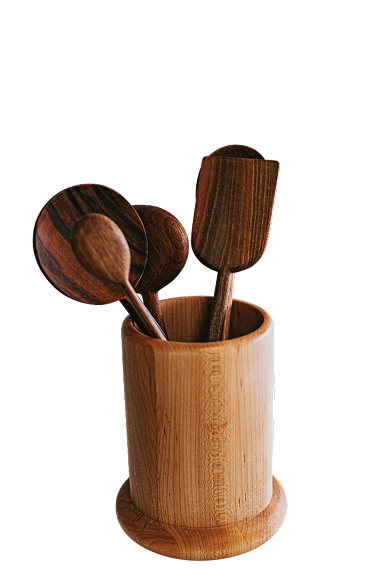 Wooden kitchen utensils, including spoons and a spatula, arranged in a cylindrical wooden holder.