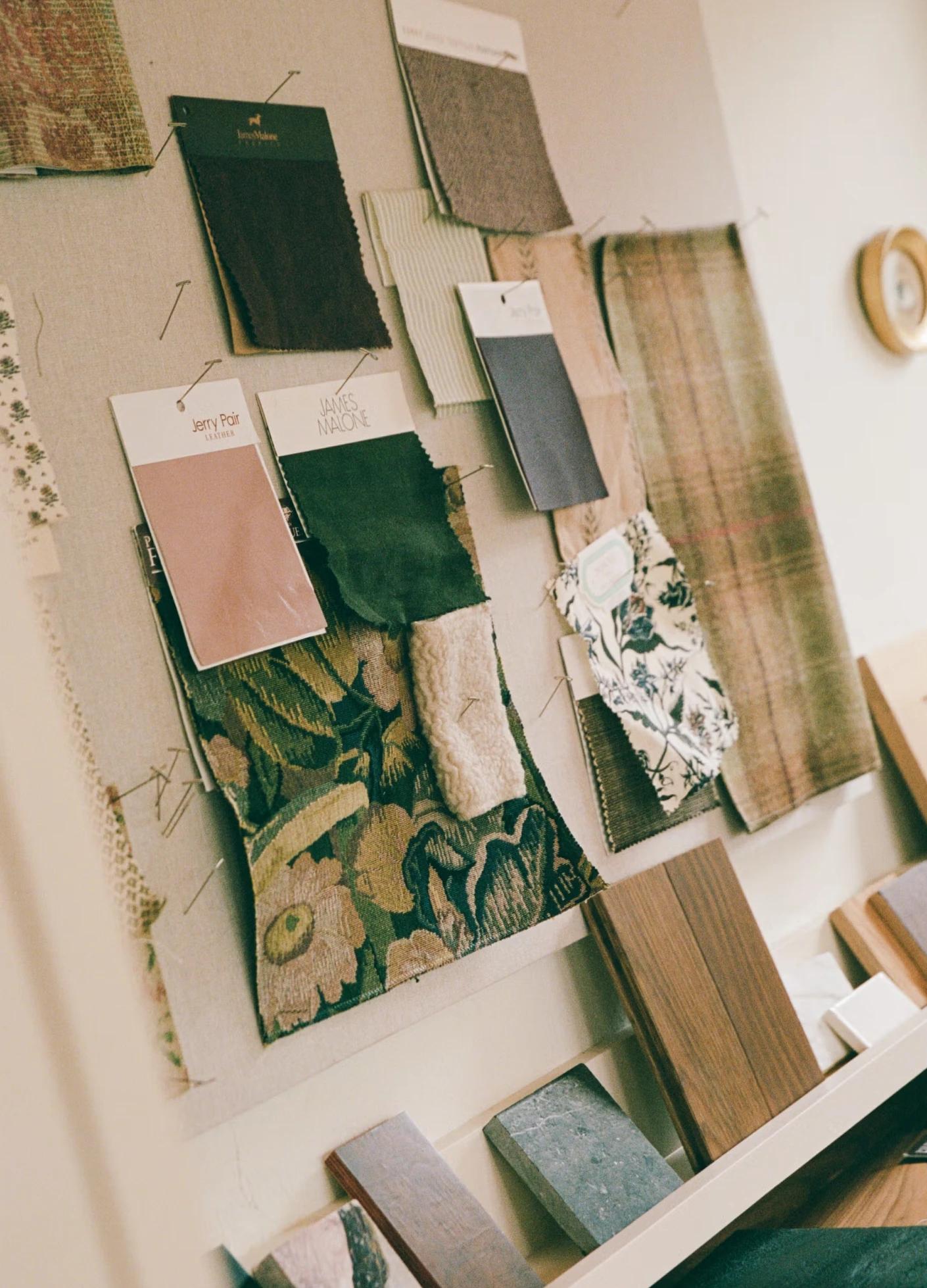 A mood board showcasing a variety of fabric swatches and wood samples pinned to a textured wall.