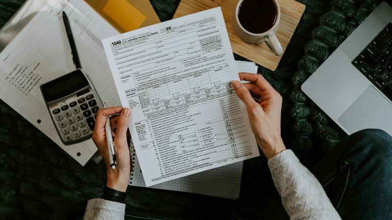 S Corp owner reviewing tax forms with a calculator and laptop during year-end tax planning