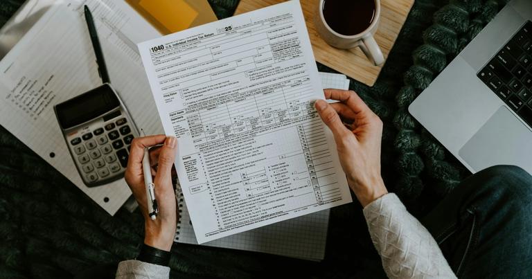 S Corp owner reviewing tax forms with a calculator and laptop during year-end tax planning