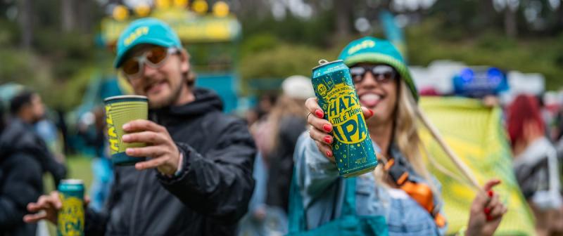 Festival-goers holding Hazy Little Thing beer cans and pint glasses