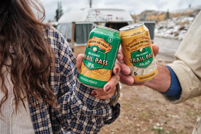 Two friends cheers with cans of Sierra Nevada non-alcoholic Trail Pass.