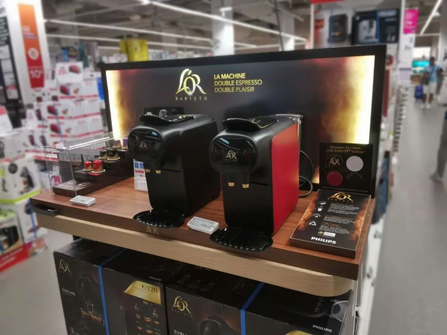 Two L’OR Barista coffee machines on lit shelf