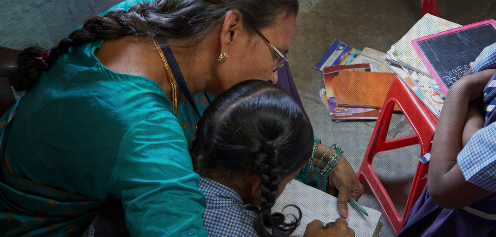 A teacher helping a pupil with her writing