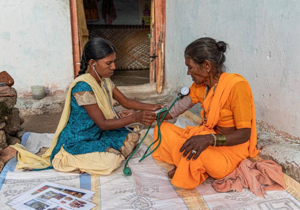 A community health worker checking a woman's blood pressure
