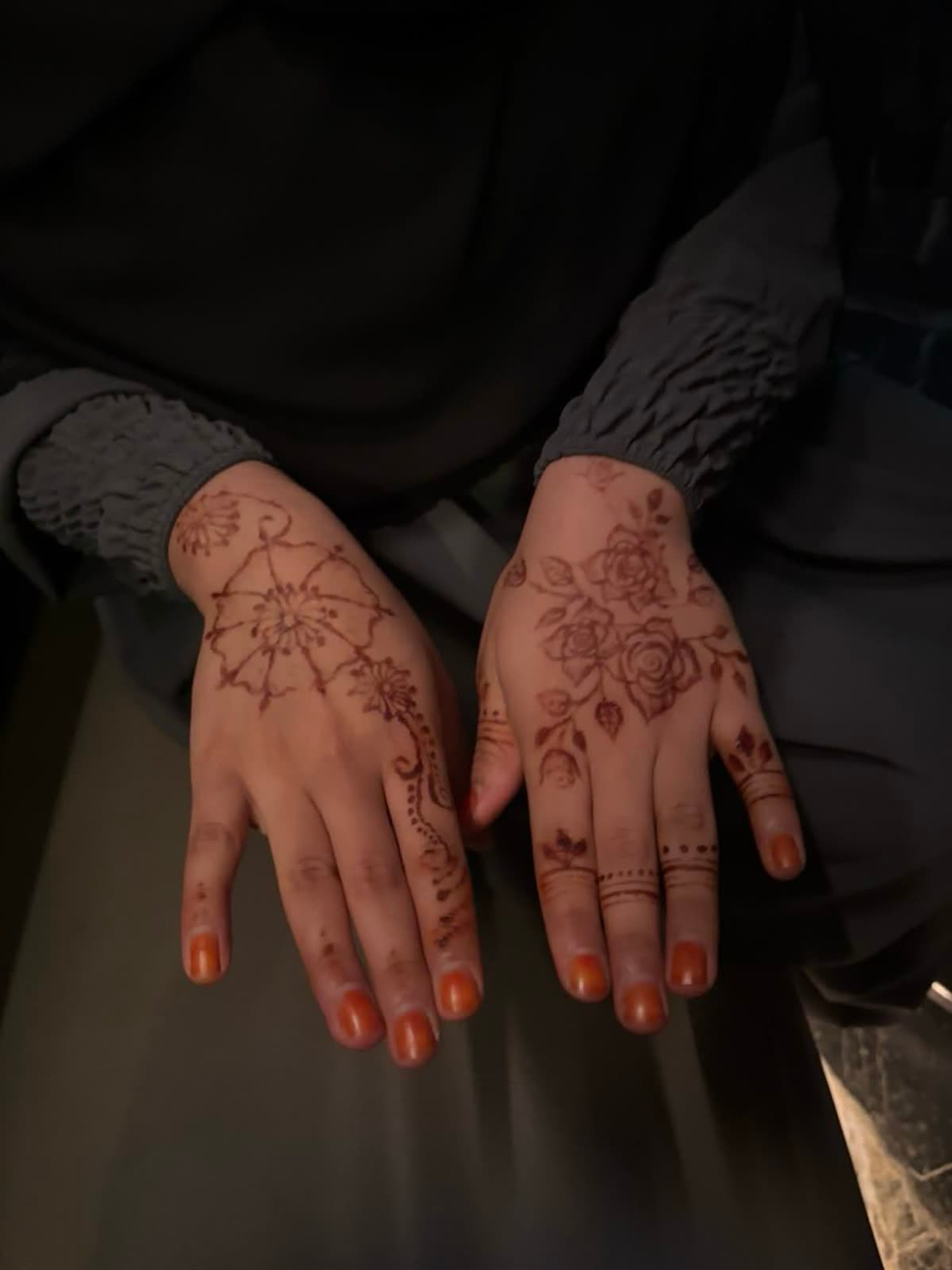 Natural henna across both hands, a central mandala with trailing roses