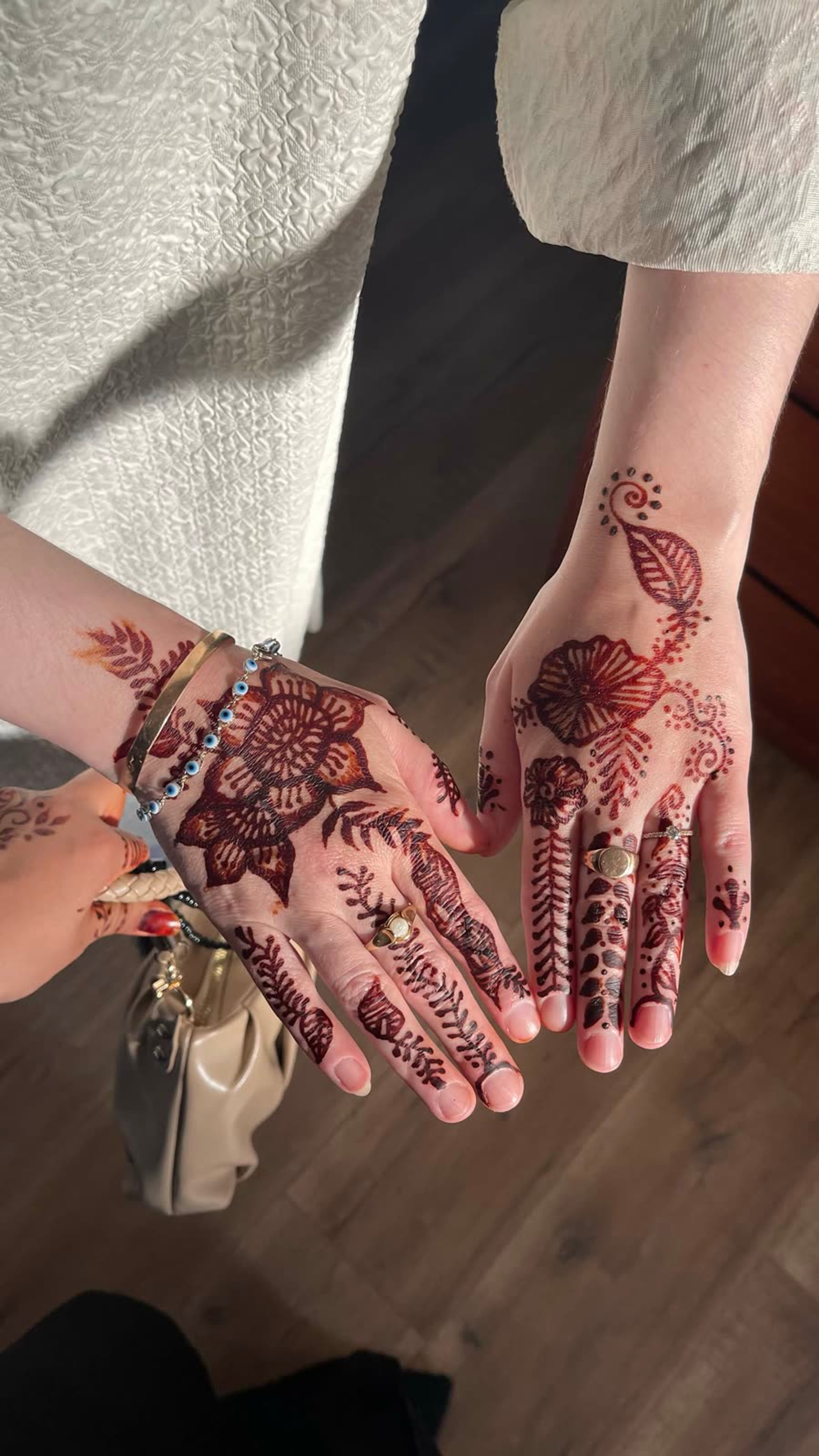 Reddish natural henna florals across two pairs of hands