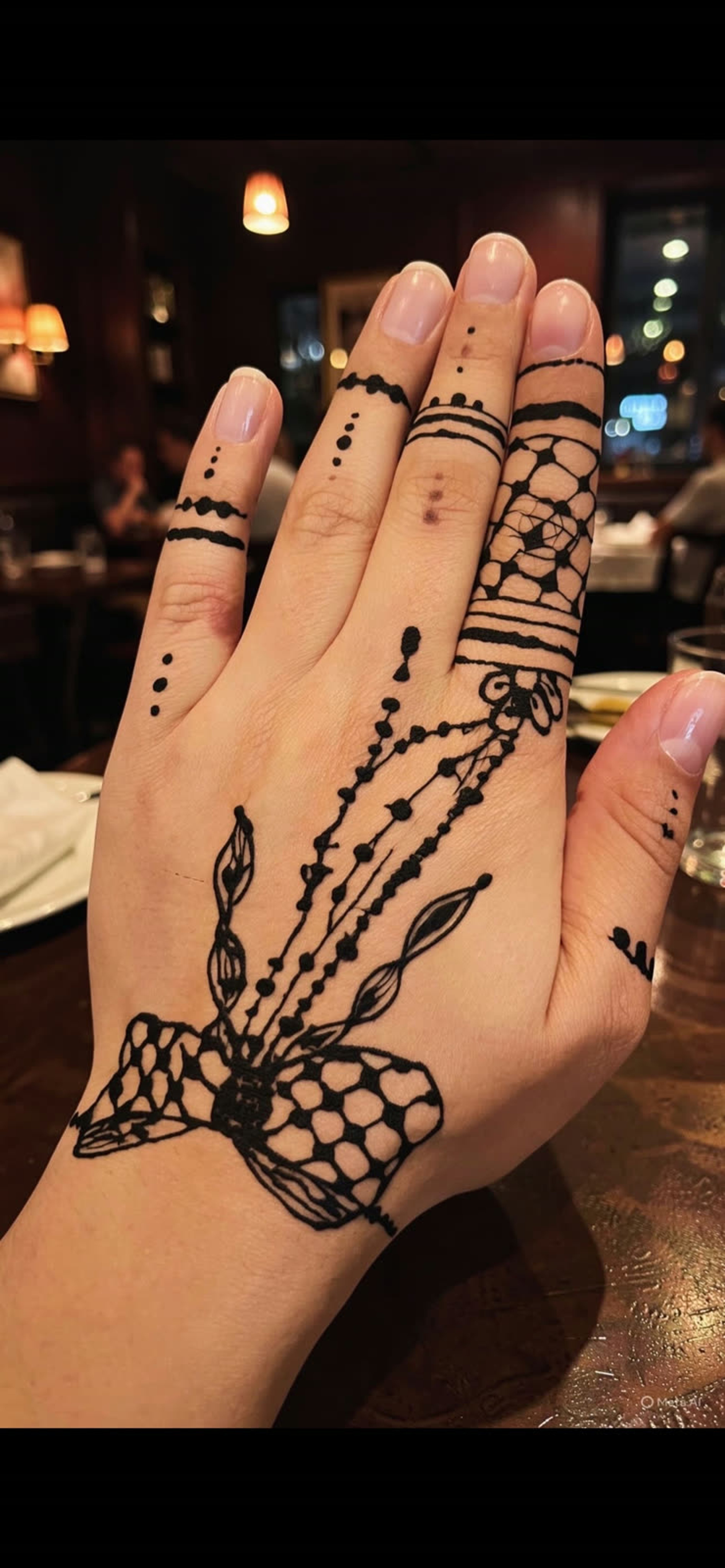 Black henna geometric and lacework across the back of the hand