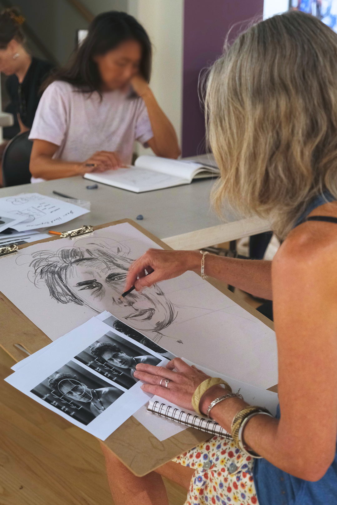 Workshop participants with drawing materials and reference images.