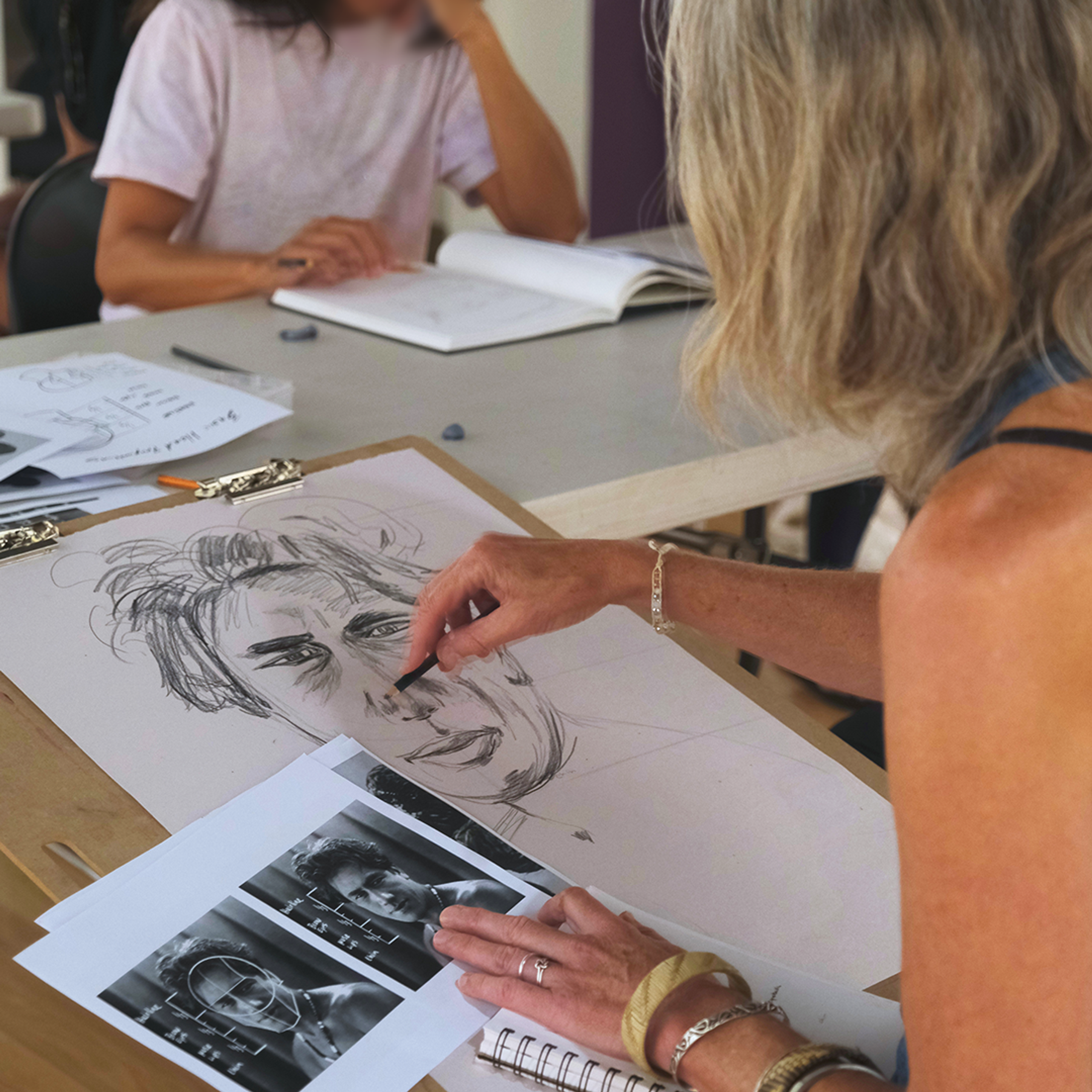 Workshop participants with drawing materials and reference images.