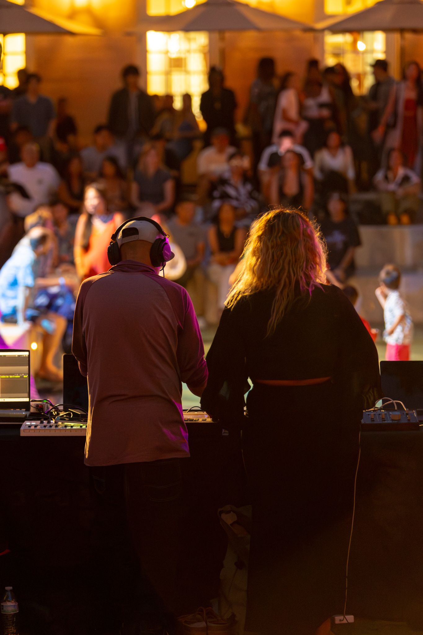 Evening in an outdoor space with colorful lighting and a deejay setup.