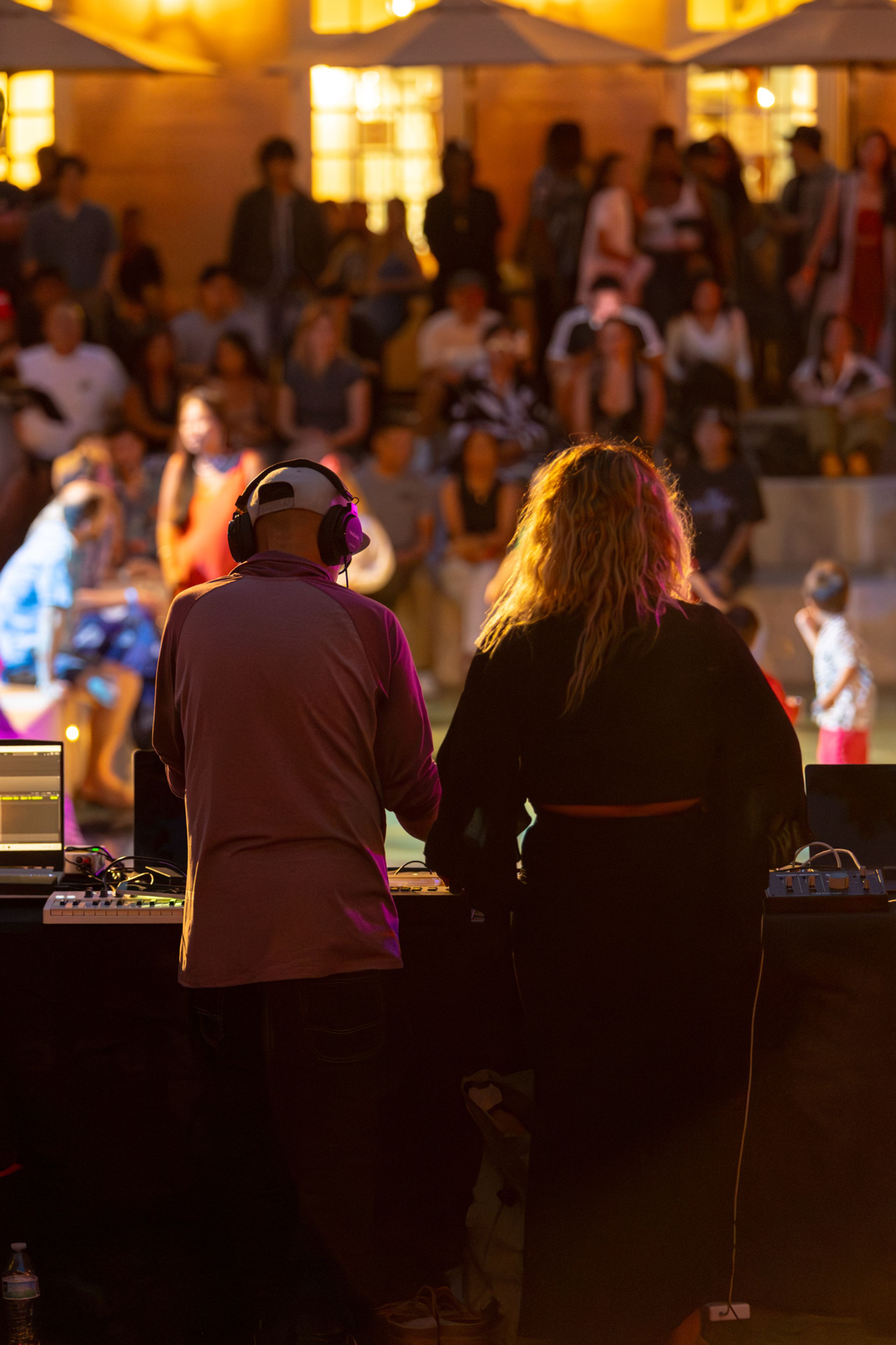 Evening in an outdoor space with colorful lighting and a deejay setup.